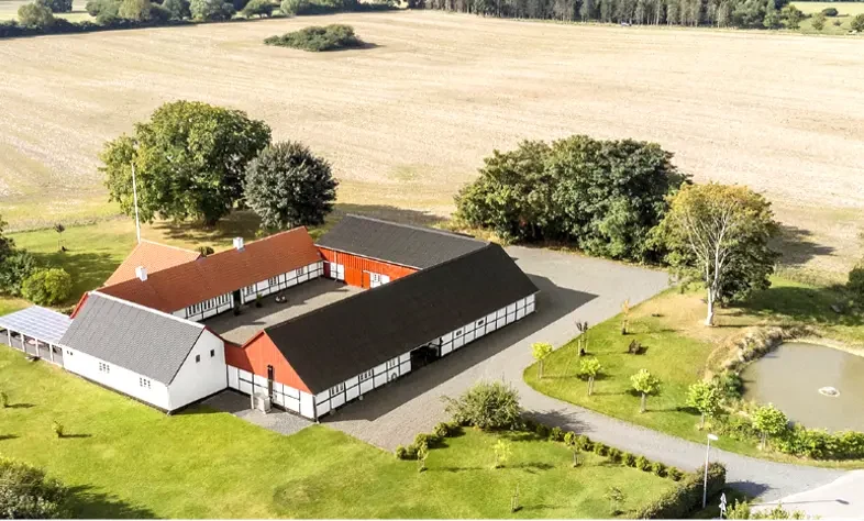 Luftfoto af Humlebækgård med staldbygninger, gårdsplads og de omkringliggende marker